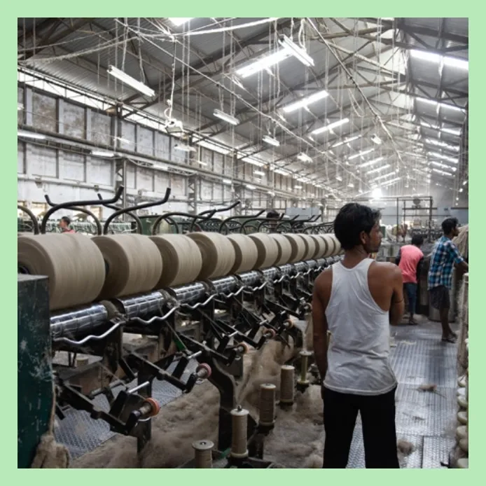 Workers monitoring jute yarn spinning machines in a textile manufacturing unit
