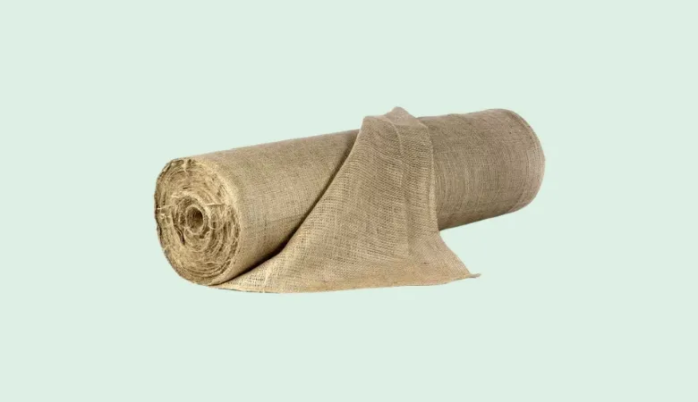 Large roll of natural hessian jute fabric partially unrolled on a flat surface.