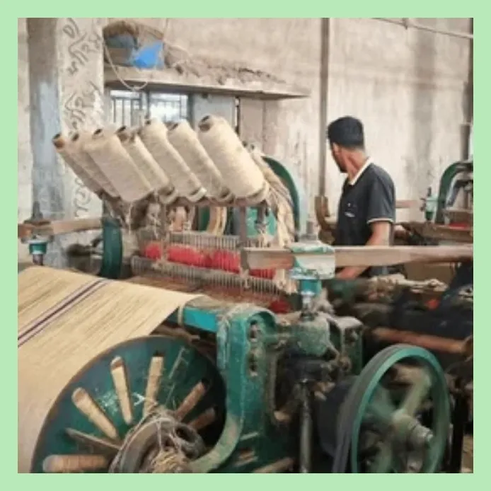 Worker operating jute weaving machine in a textile mill producing hessian fabric