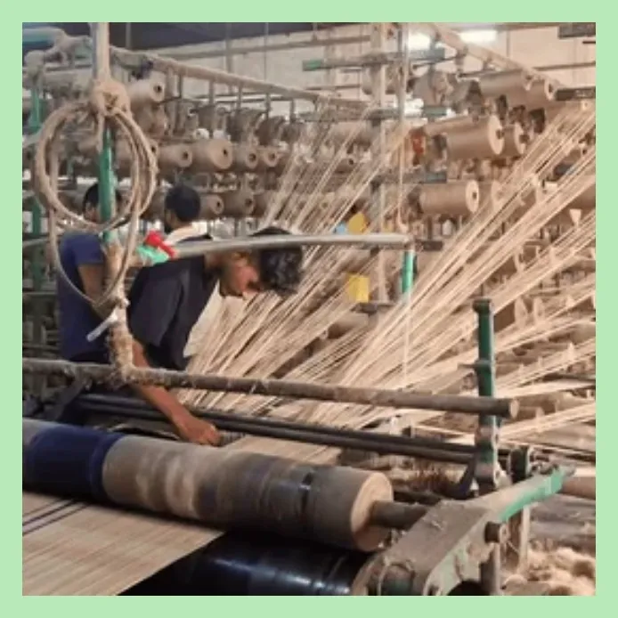 Worker weaving jute fabric on a spinning machine