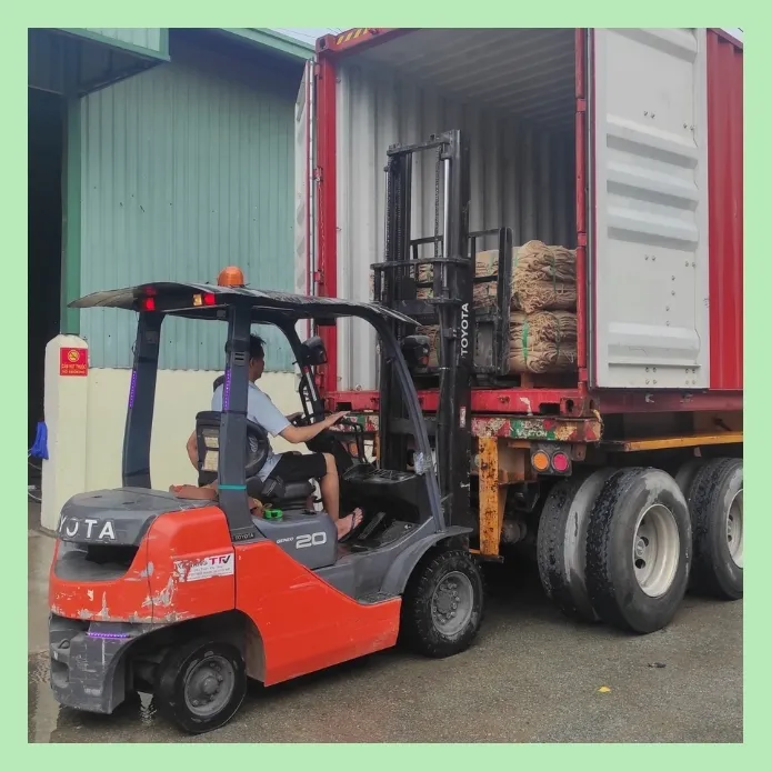 Forklift operator loading jute product bales into a shipping container for export at a warehouse