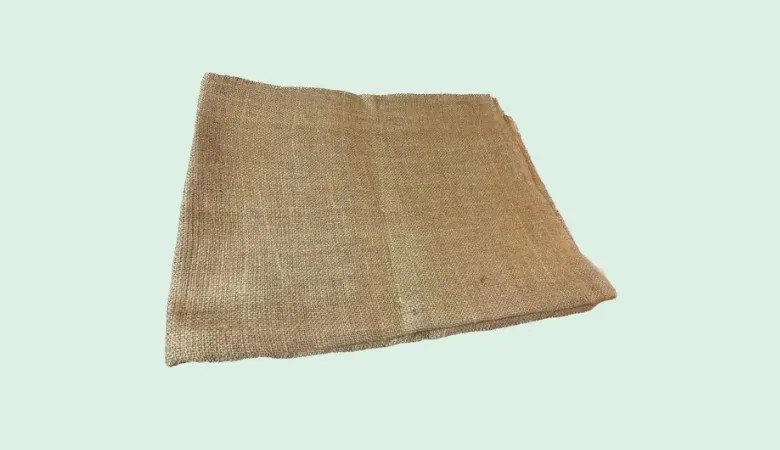 Folded piece of plain brown hessian jute cloth on a light background.