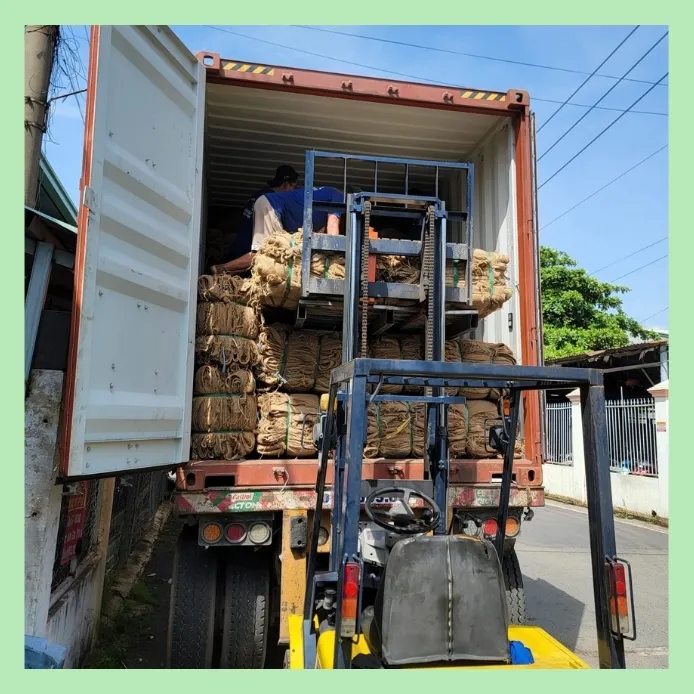 Forklift loading bales of jute rope into a shipping container for export logistics